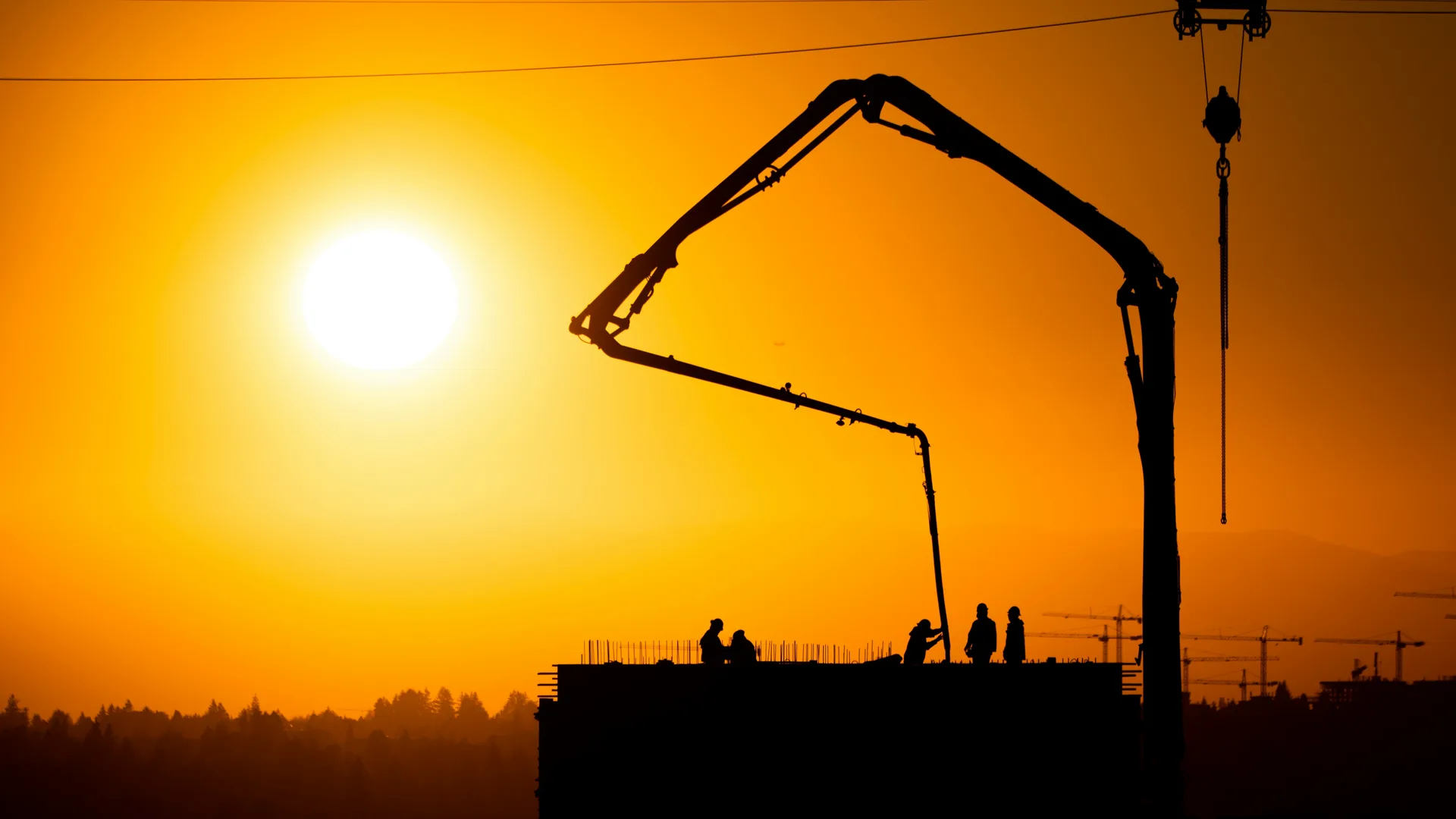 concrete boom pump on a Boston construction site at sunset